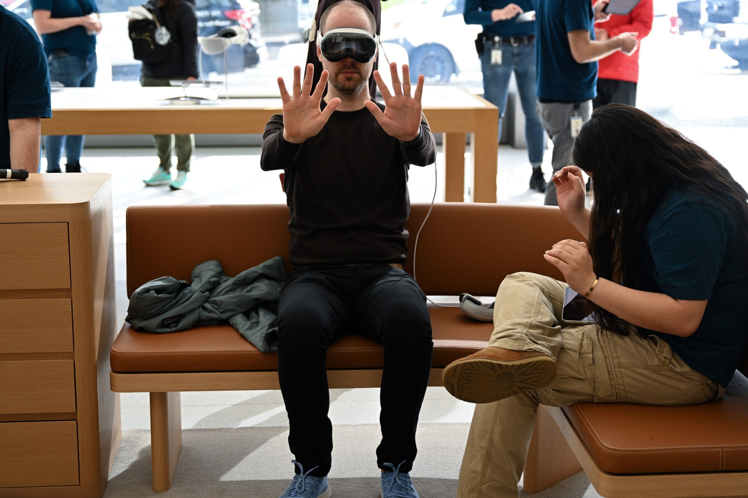 A man wearing a Vision Pro is guided by an Apple employee during a demo. Some users complained of motion sickness